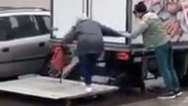 Hombres ayudan a señora de la tercera edad a llegar a su carro en estacionamiento inundado