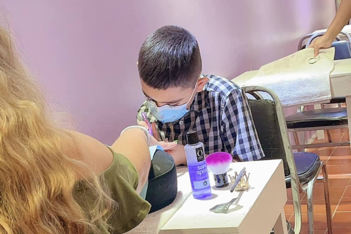 Niño aprende a poner uñas para apoyar a su mamá a pagar la operación de su hermanito